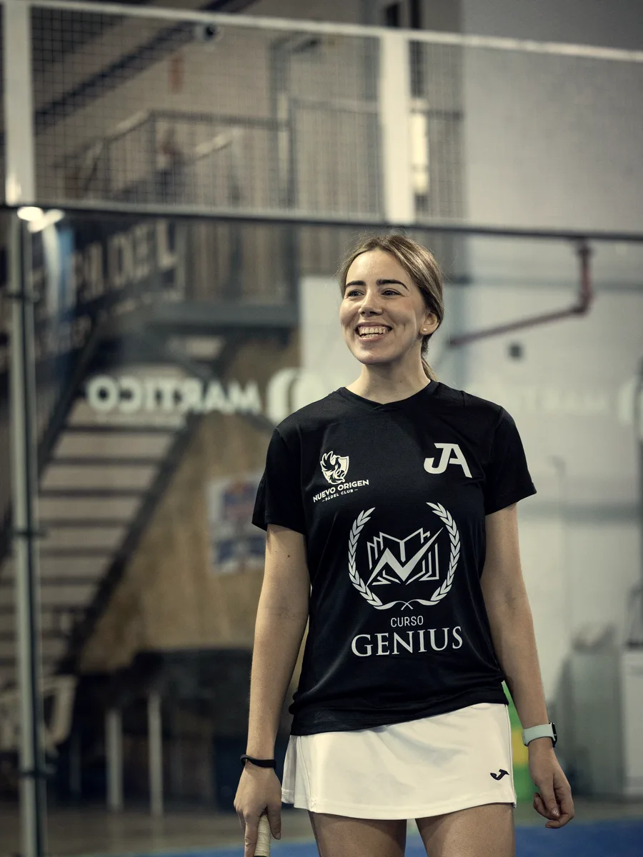 A player smiles standing by the court in the team shirt