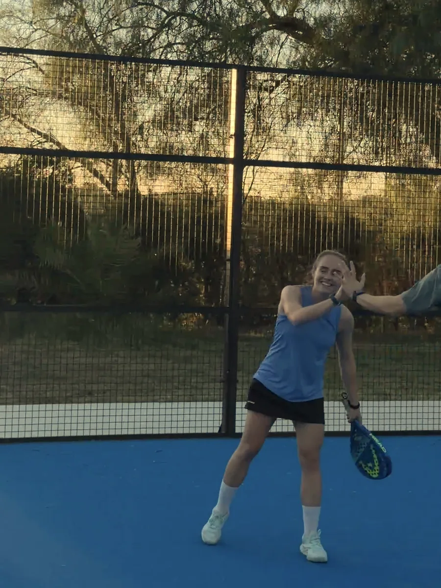 A player smiles and high-fives someone on court at sunset