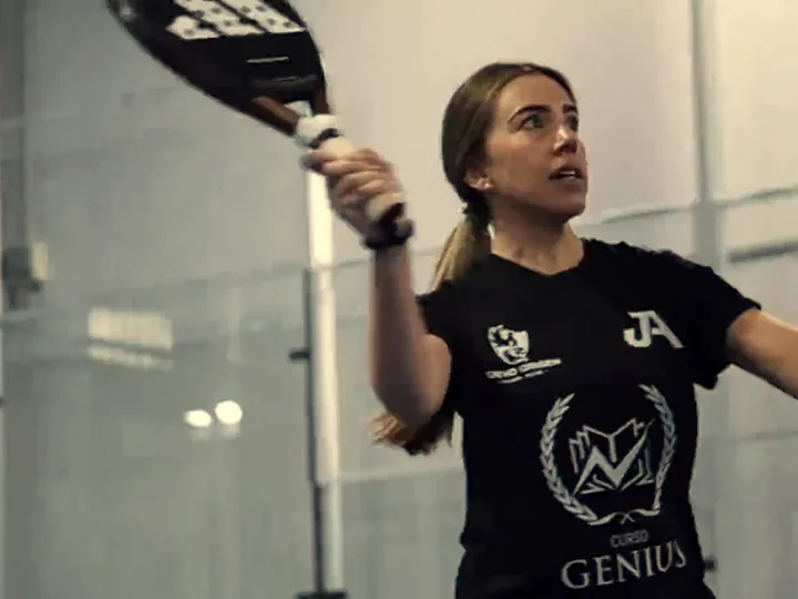A player with her racket raised inside the hall