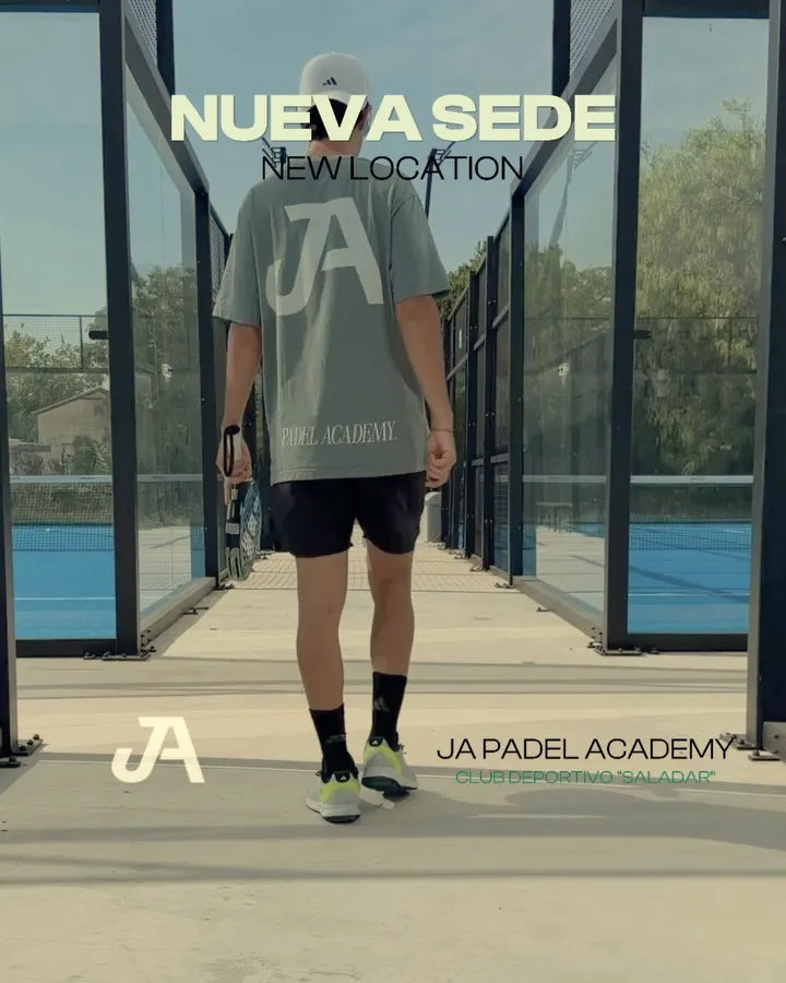 A player in a JA shirt walks away down the walkway between the outdoor courts.