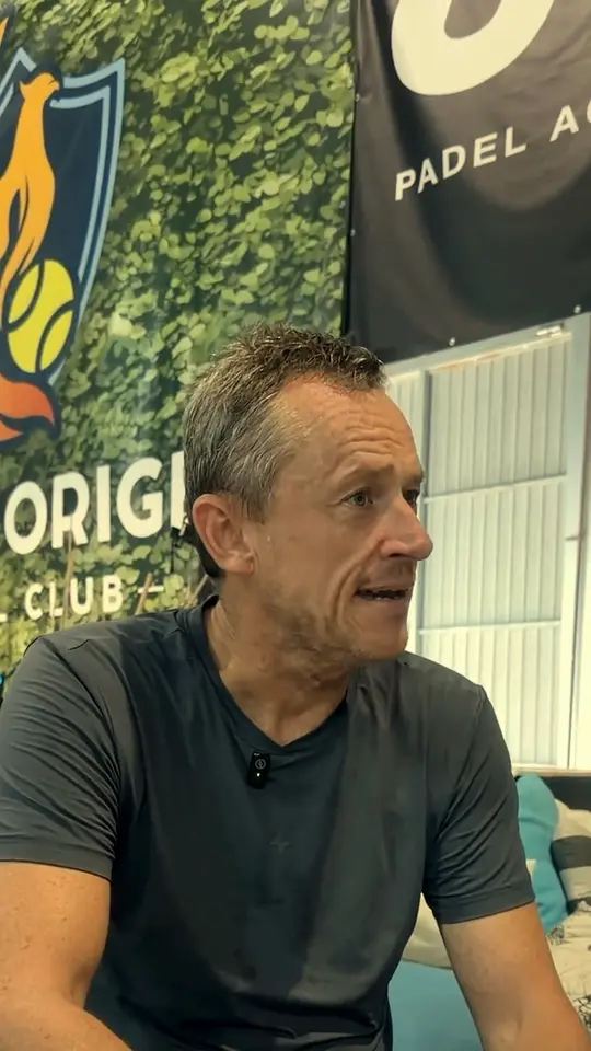 A player talks, seated in front of the club and JA Padel Academy banners.