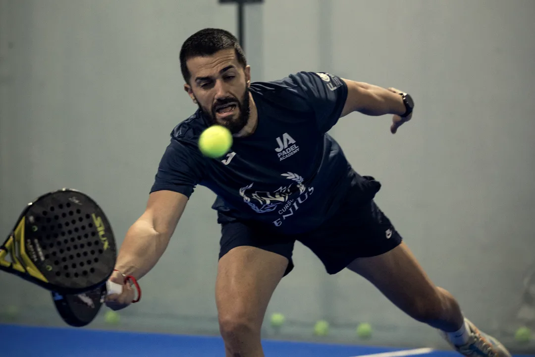 A player stretches to reach a low ball on an indoor court